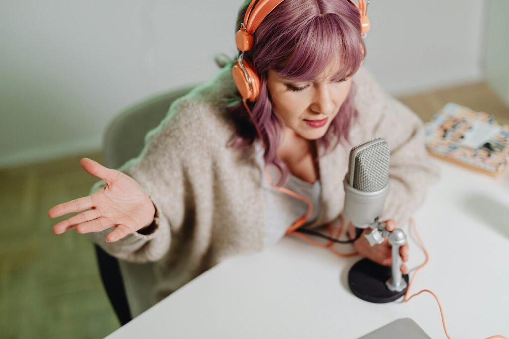 Woman in Brown Sweater Holding Silver Micrphones